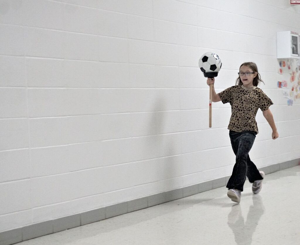 girl carrying soccer ball on plunger