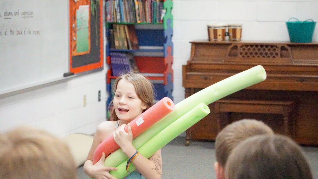 girl with arms full of pool noodles