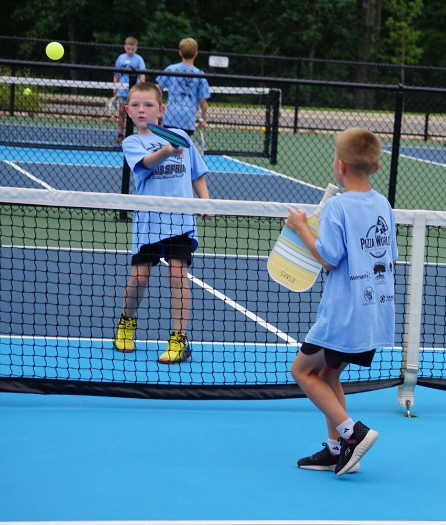 A boy hitting a pickleball