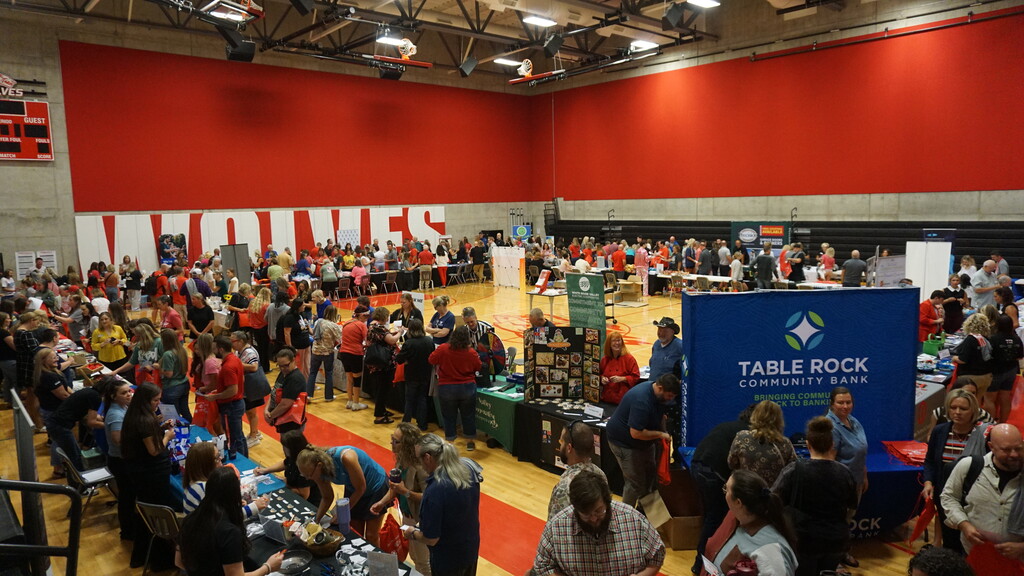 Wide shot of gym full of vendors and tables.