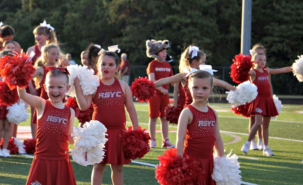 A youth cheerleadering waving to the crowd.