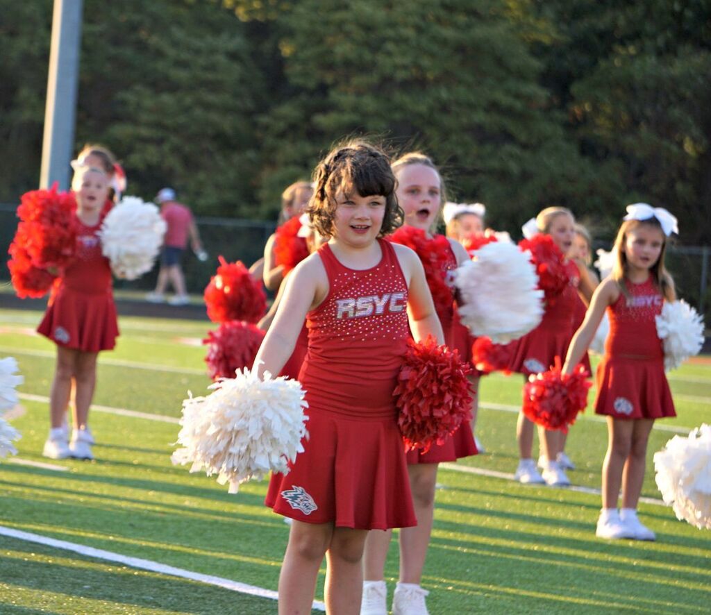 A youth cheerleader smiling while performing
