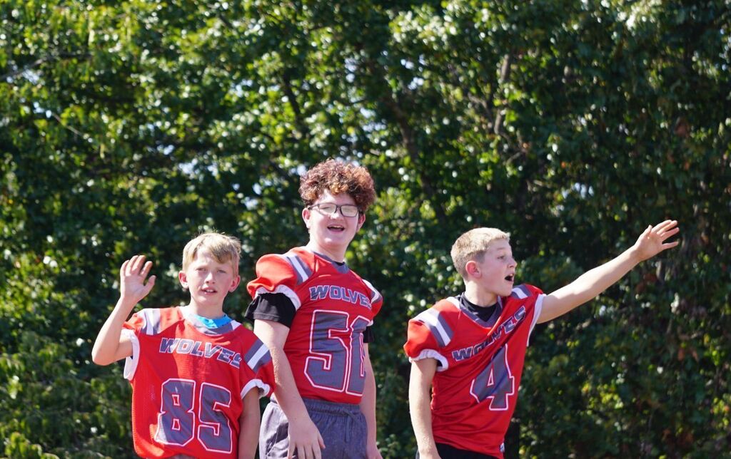 Middle School football players wave from a float.