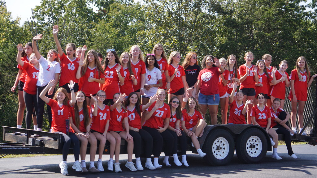 Middle School volleyball players ride on a float.