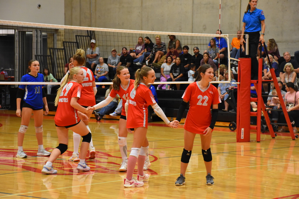 8th grade volleyball players smile and hold hands