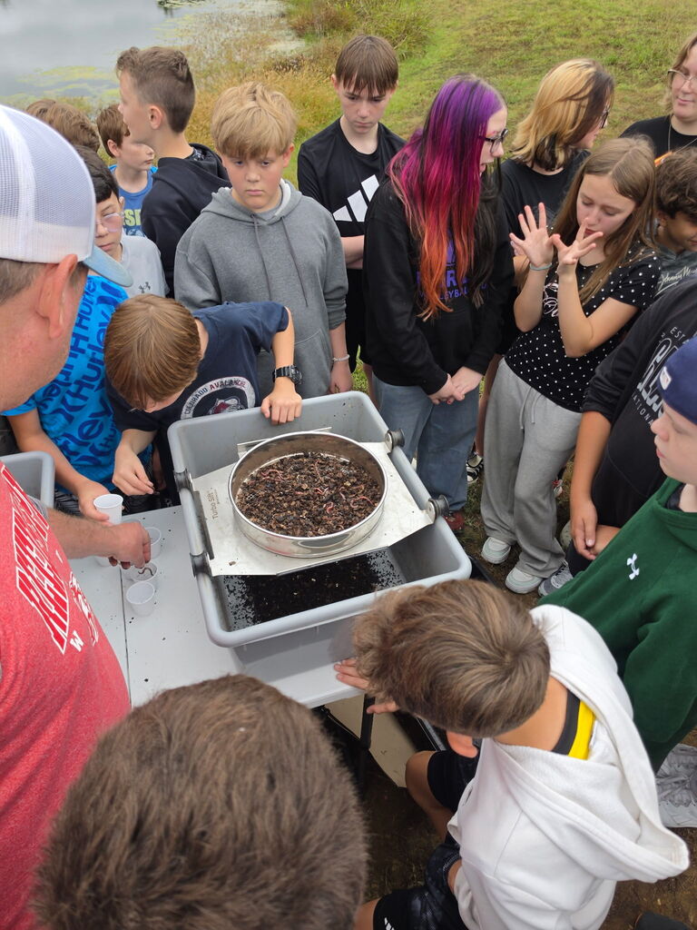 Kids look at can full of worms.