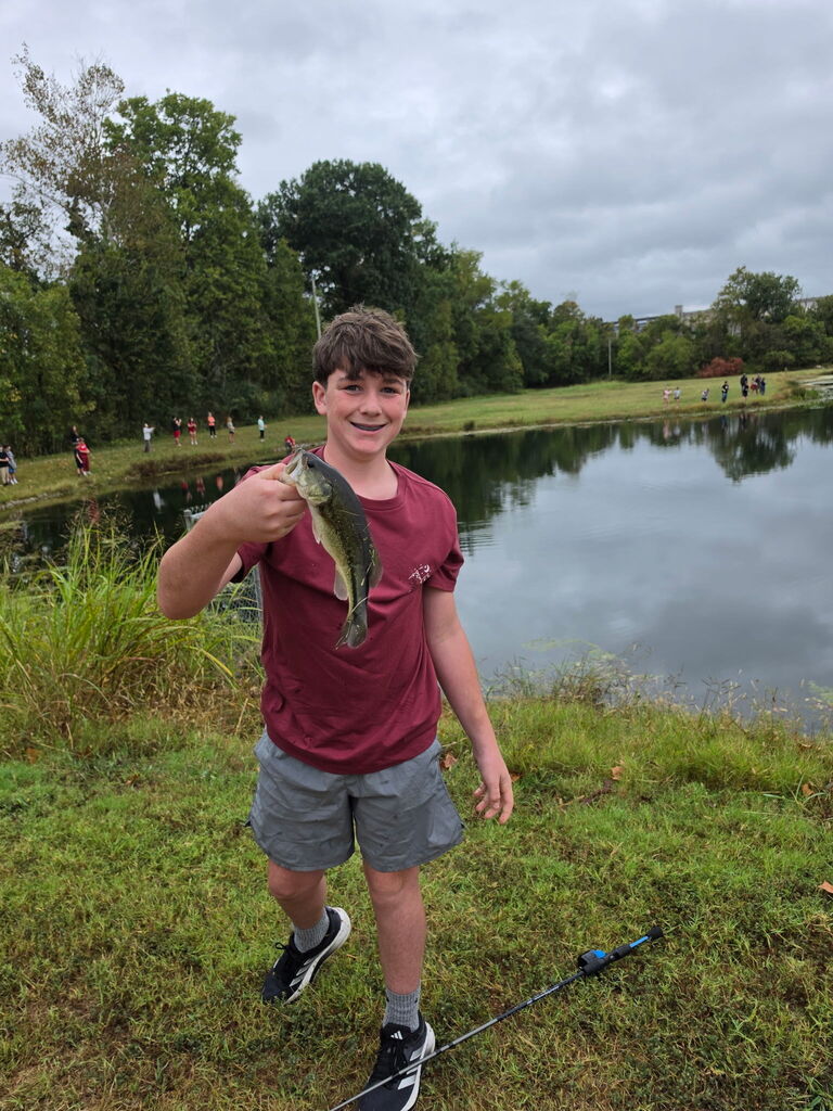 Boy holds up fish he caught.