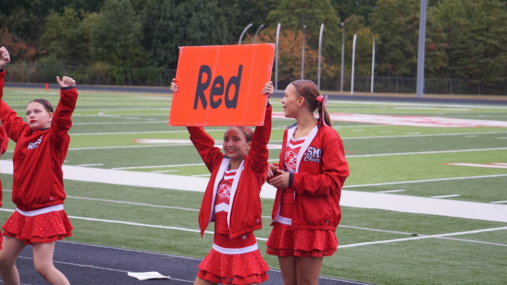 Cheerleader holds up "Red" sign.