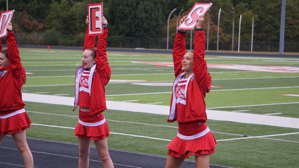 Two cheerleaders hold up signs.