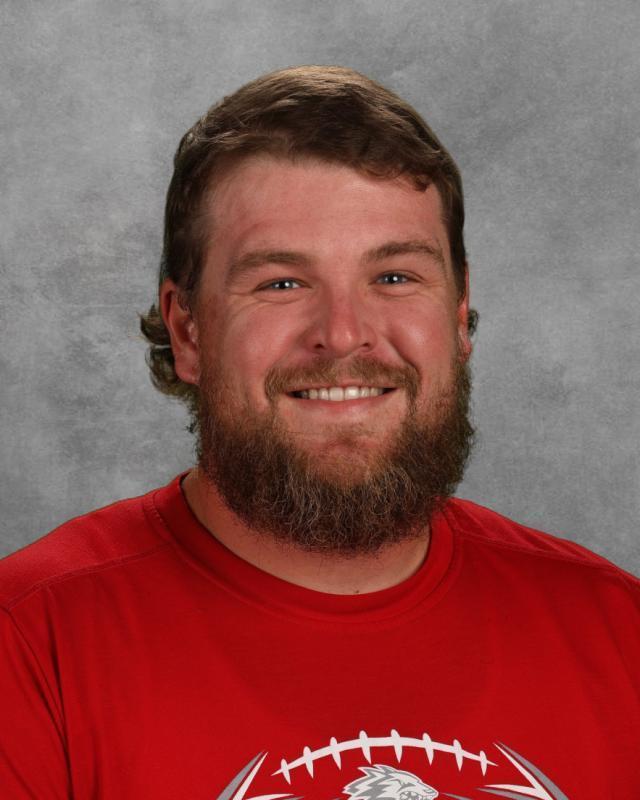 man with dark hair, beard, and red t shirt