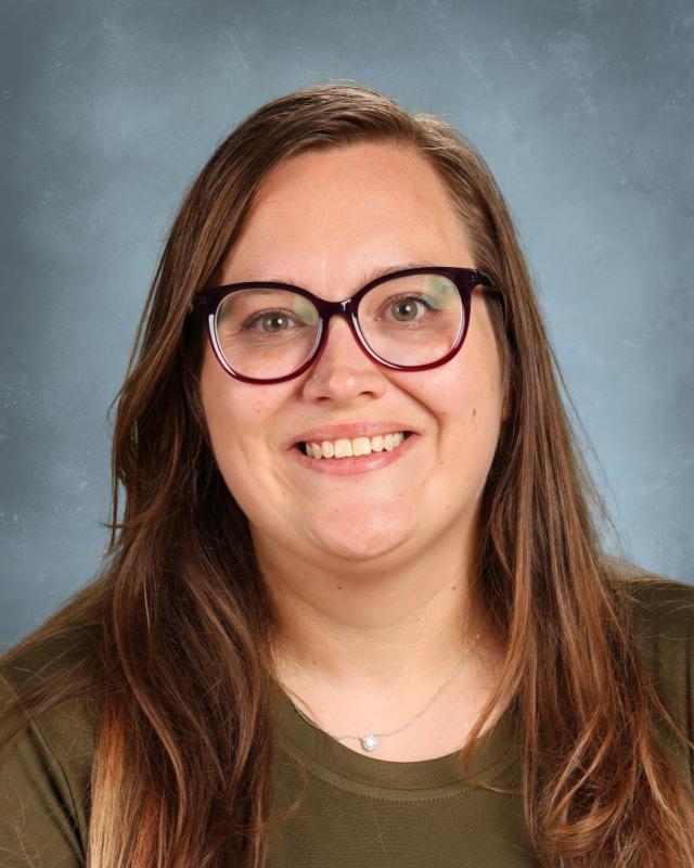 woman with glasses and brown hair wearing a green shirt