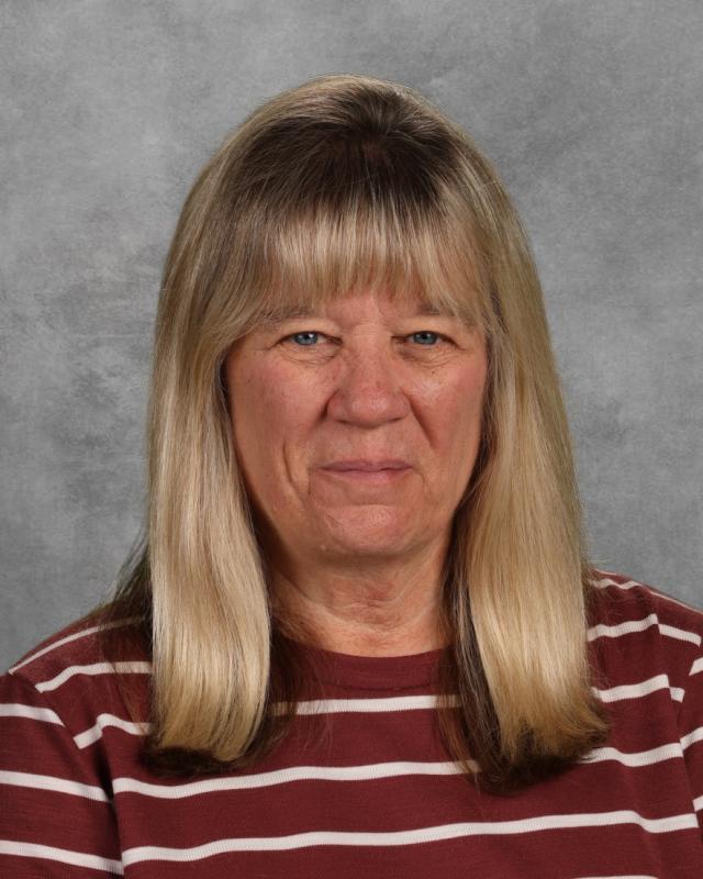 woman with blond hair weraing a brown and white striped shirt