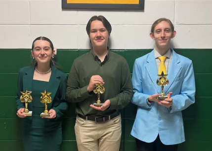 girl and two boys holding trophies