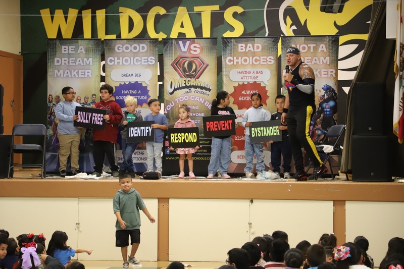 AES Assembly students and presenter on stage holding positive signs