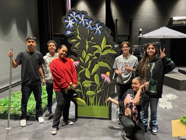 students standing in front of a wooden art cut out