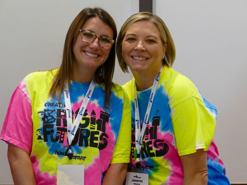 Two ladies with tie die shirt smiling and posing at the camera
