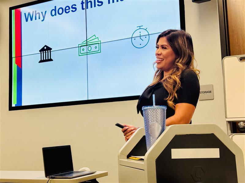 A presenter smiling at the public while showing her presentation