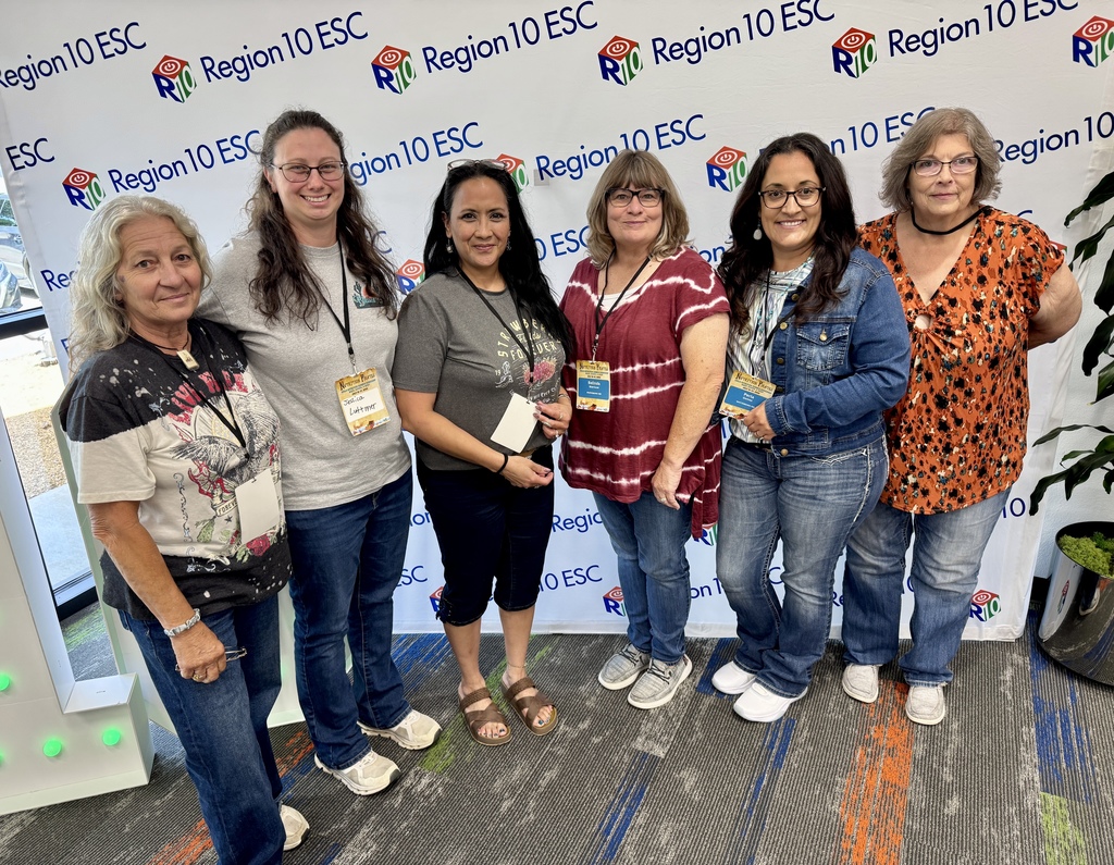 Six ladies standing in front of a backdrop that says Region 10 smiling at the camera
