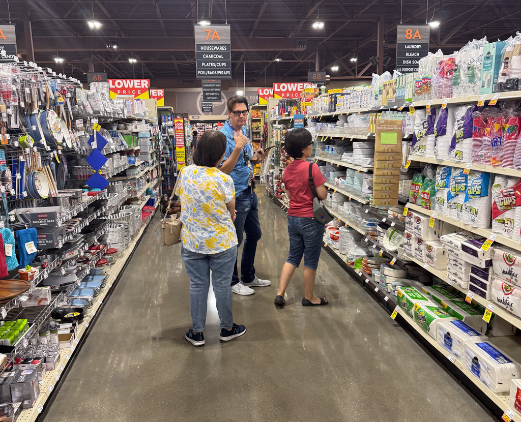 Three customers discussing products in a Lowe's store aisle.