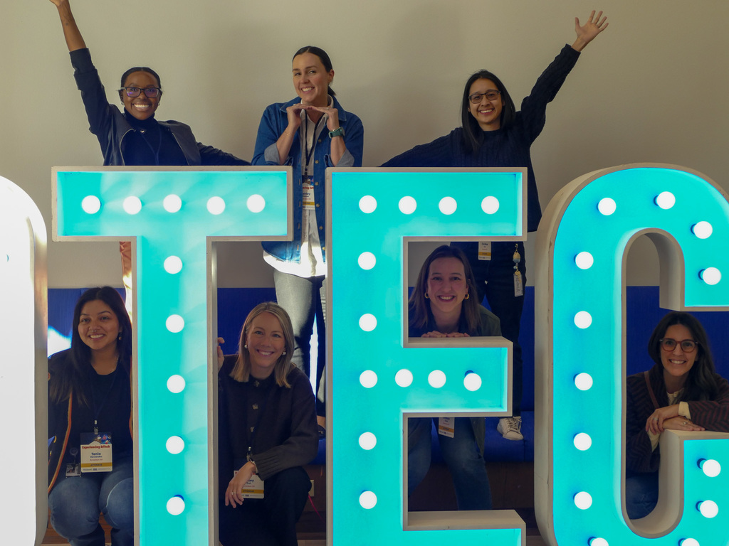 Group of people excuted smiling to the camera, behind big light up letters