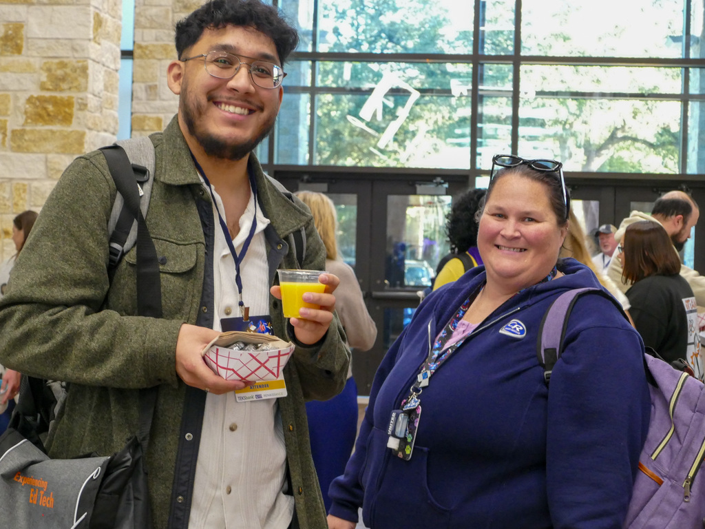 two individuals holding their breakfast smiling at the camera inside the building