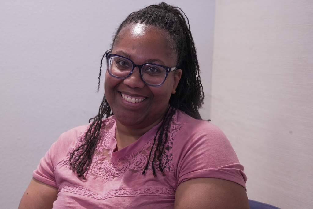 A person wearing glasses, she's smiling to the camera.