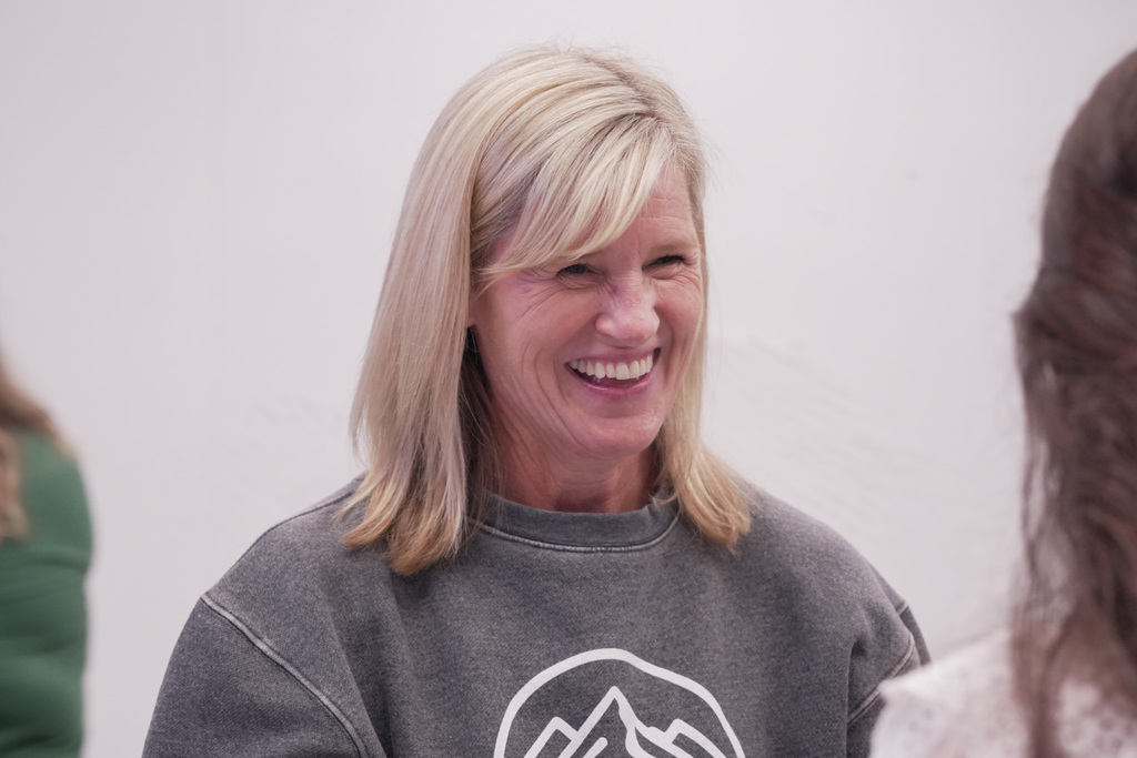 A lady smiling while looking at another person in a room. 