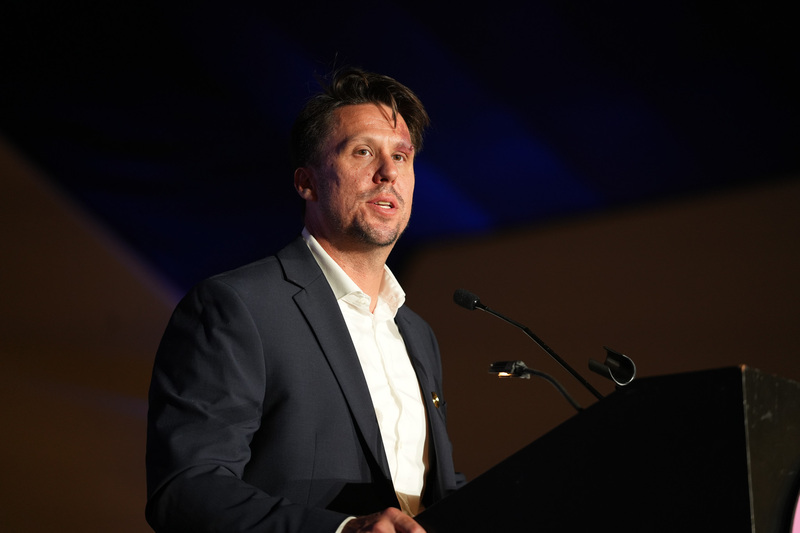 Man speaking into microphone on stage.