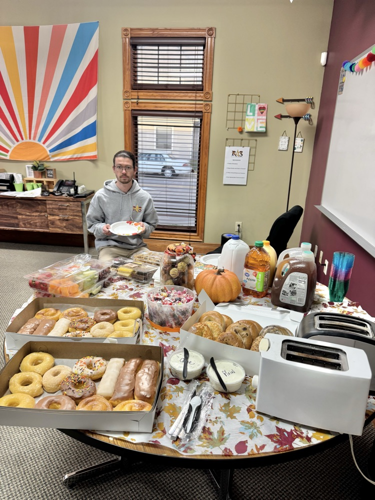 table full of fruit, donuts, and bagels