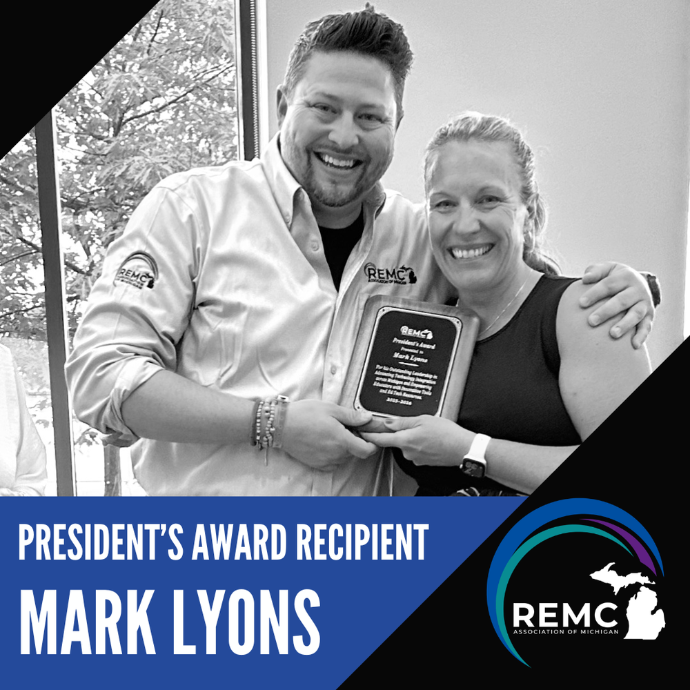 A photo of Mark Lyons while holding his REMC President’s Award plaque beside another person smiling. The graphic features a photo of the recipients and includes the text, “President’s Award Recipient Mark Lyons,” along with the REMC Association of Michigan logo displayed in lower right corner.