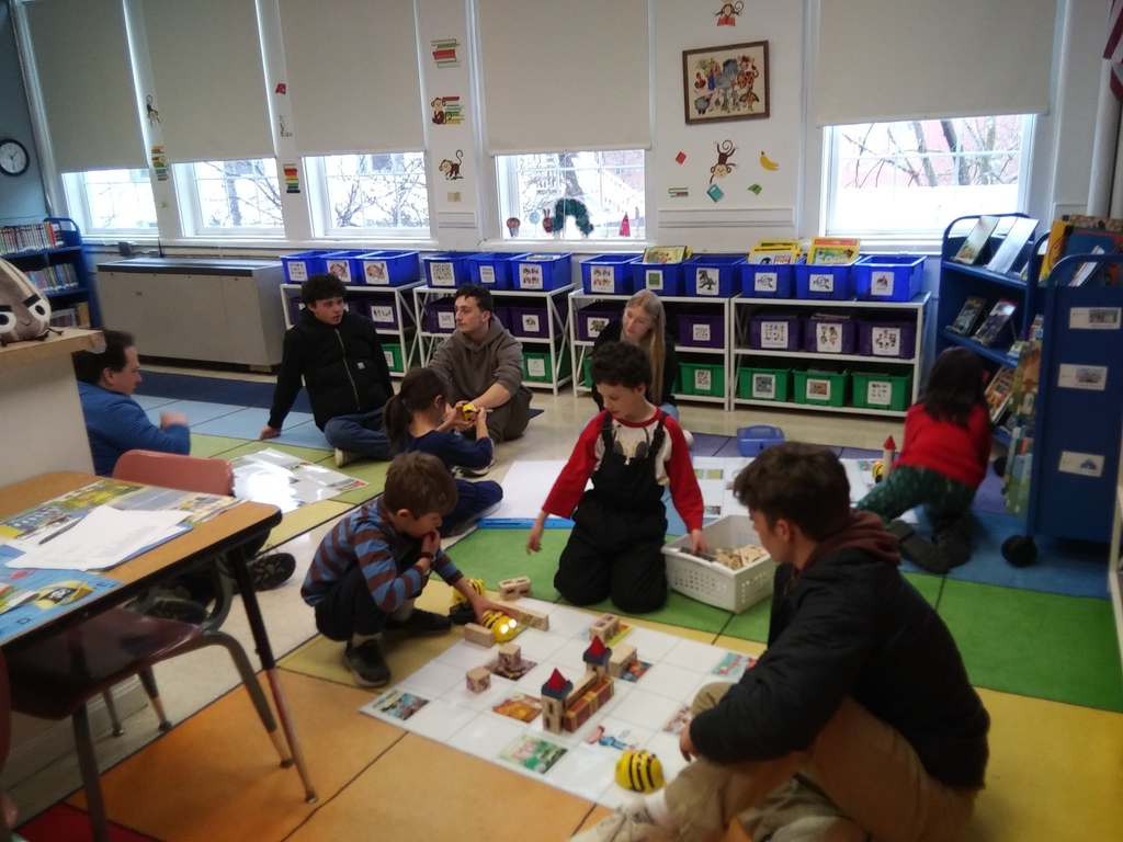 elementary students and an older peer working on the bee bot coding