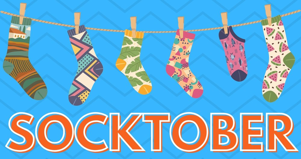 Colorful socks hanging on a clothesline with text stating "SOCKTOBER - bring new socks to school October 20-30 to help those in need!"