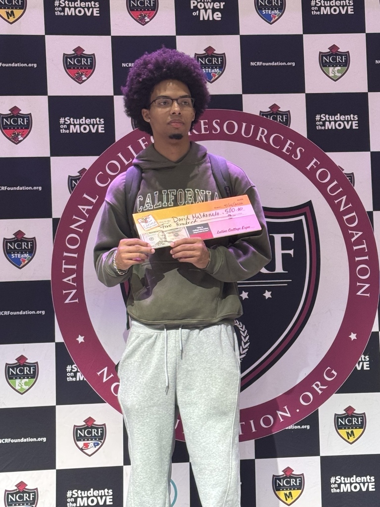 English: A Rich Township student stands in front of the National College Resources Foundation backdrop holding a $500 award check. Español: Un estudiante de Rich Township posa frente al fondo de la National College Resources Foundation sosteniendo un cheque de premio de $500.