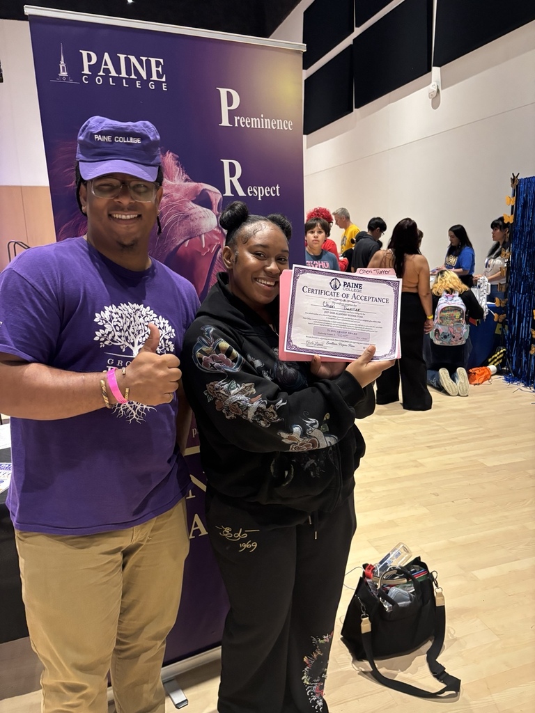 English: A Rich Township student smiles while displaying a Paine College Certificate of Acceptance beside a college representative at the expo. Español: Una estudiante de Rich Township sonríe mientras muestra un Certificado de Aceptación de Paine College junto a un representante de la universidad durante la feria.