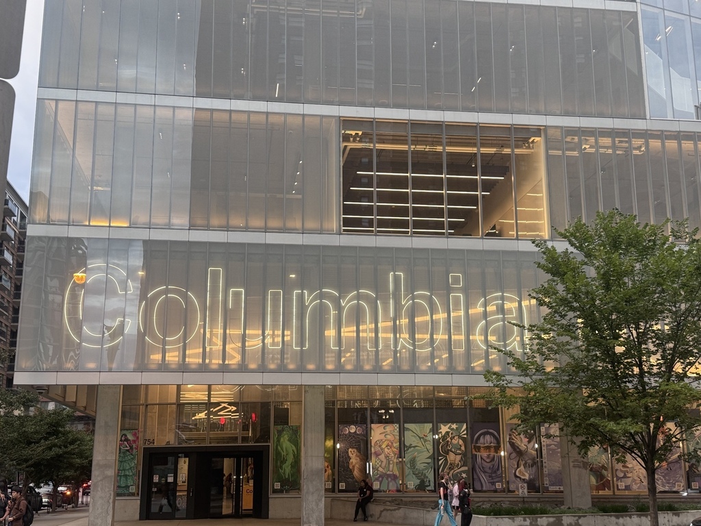 English: Exterior of Columbia College Chicago in downtown Chicago, showing the modern glass building and illuminated Columbia sign. Español: Exterior de Columbia College Chicago en el centro de Chicago, mostrando el moderno edificio de vidrio y el letrero iluminado de Columbia.