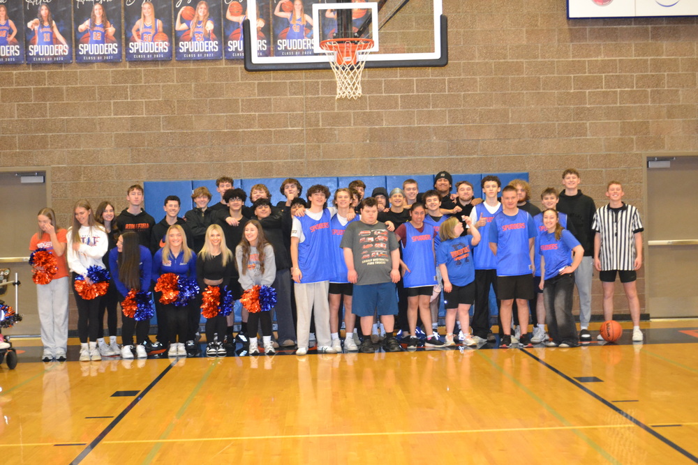 A group of high school students posed together in a basketball gym