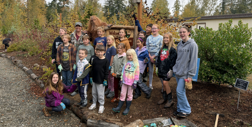 17 elementary school students pose with teacher Jackie Bergeron and Sasquatch at the fall trail cleanup at South Ridge Elementary School