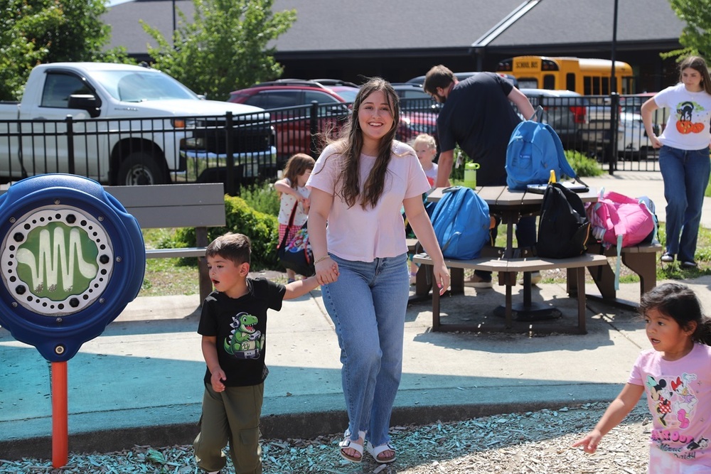 RHS senior Marlo Denniston holds a preschooler's hand at the ELC playground