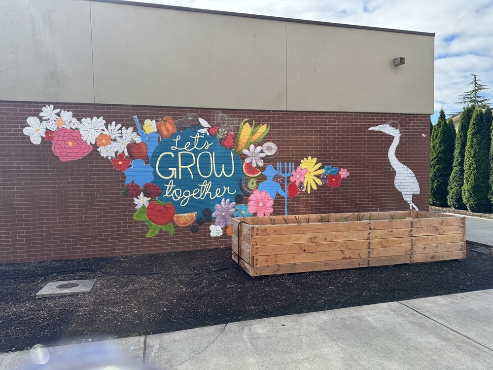 A mural that says "Let's Grow Together" painted on a brick wall