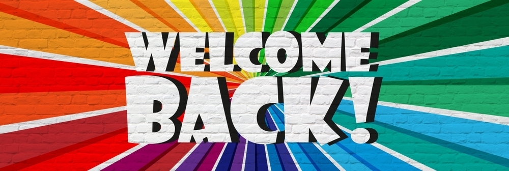 A mural painted on a brick wall that says "Welcome Back" surrounded by rays of color