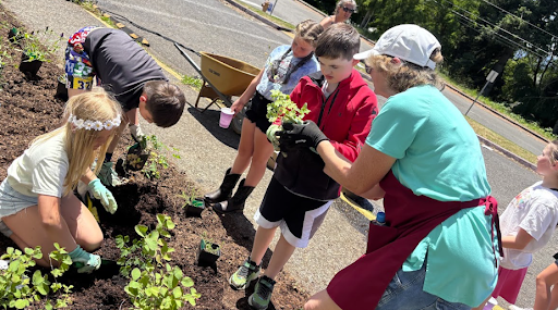 A volunteer helps students plant native plants at Union Ridge Elementary School