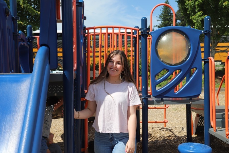 A smiling Marlo Denniston poses in front of colorful playground equipment