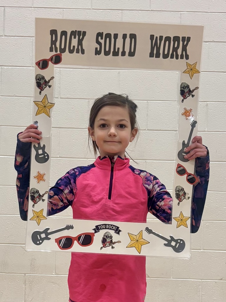 4th grade student holding sign that says Rock Solid Work