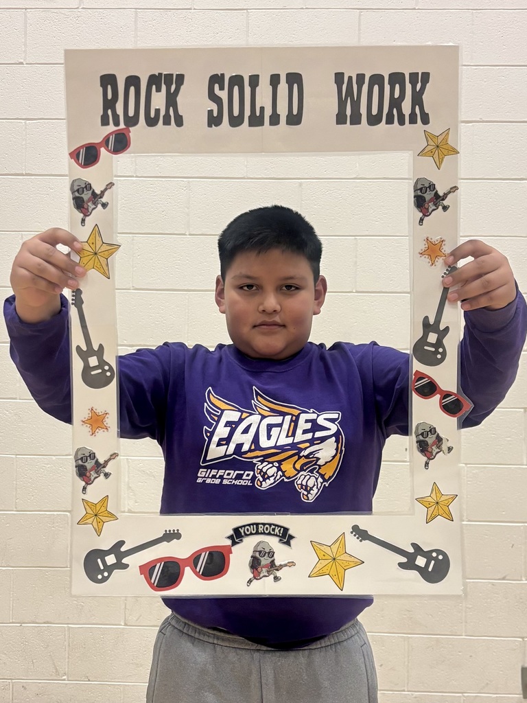 4th grade student holding sign that says Rock Solid Work