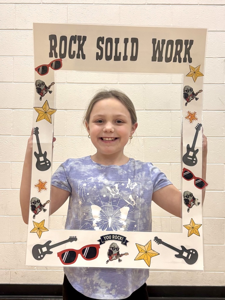 3rd grade student holding sign that says Rock Solid Work