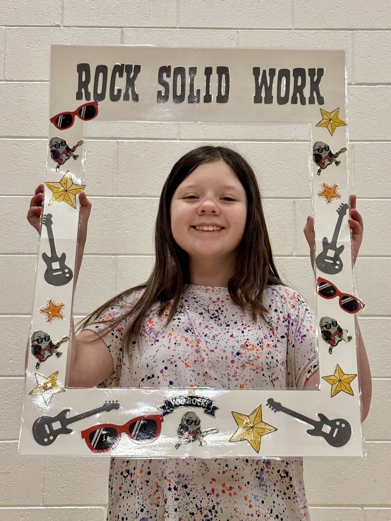 5th grade student holding sign that says Rock Solid Work