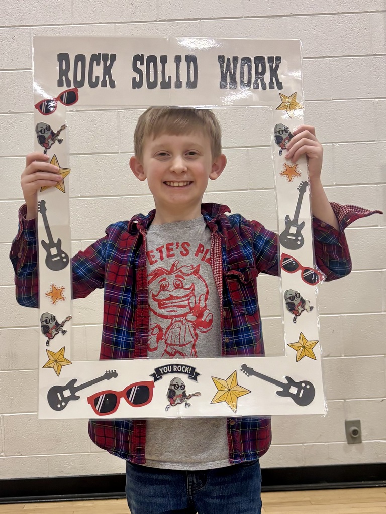 3rd grade student holding sign that says Rock Solid Work