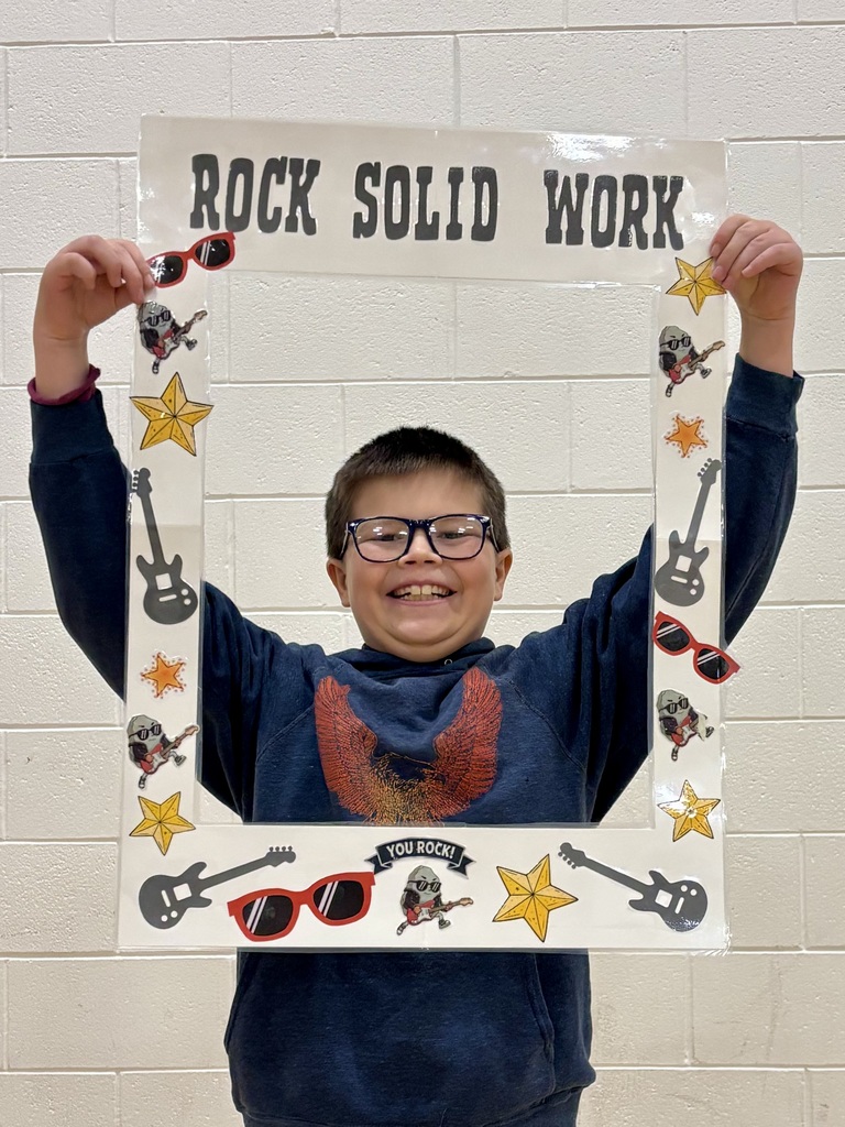 5th grade student holding sign that says Rock Solid Work