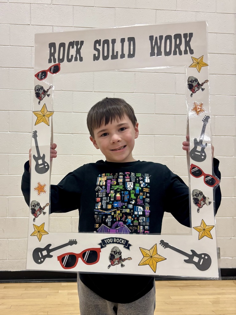 1st grade student holding sign that says Rock Solid Work