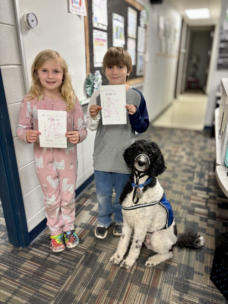 kids holding perfect papers with facility dog